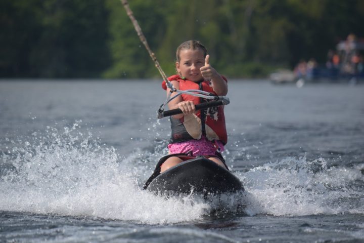 A camper is happy to be out kneeboarding at Arrowhead Camp.